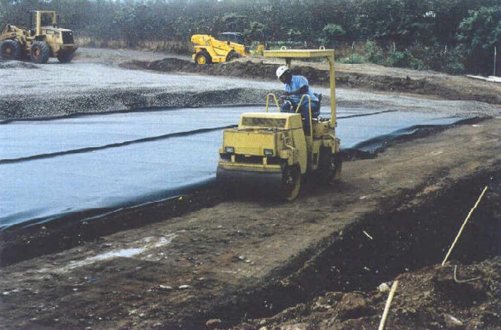 A technician installing an impermeable geomembrane cap over the backfilled area to prevent further water infiltration